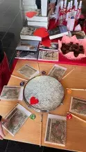 : stół z książkami-nagrodami. Na zdjęciu koło fortuny: serce wskazuje wygrany fant.